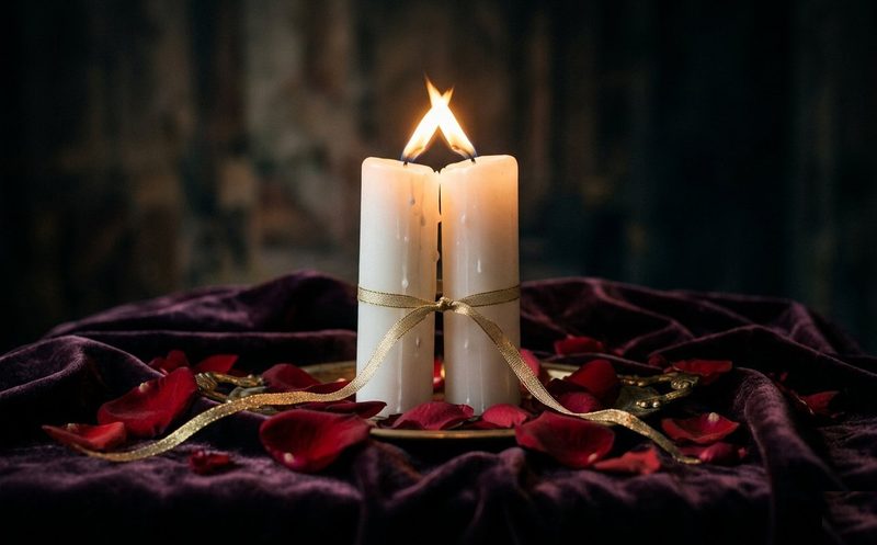 Due candele bianche e rose davanti a un altare di armonizzazione di coppia